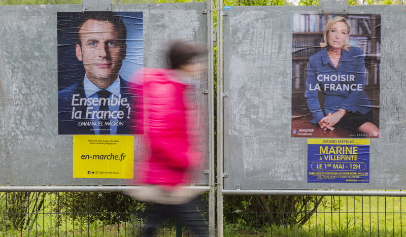 Una mujer pasa frente a los carteles de los candidatos a las presidenciales francesas. Foto: Radu Razvan/Shutterstock